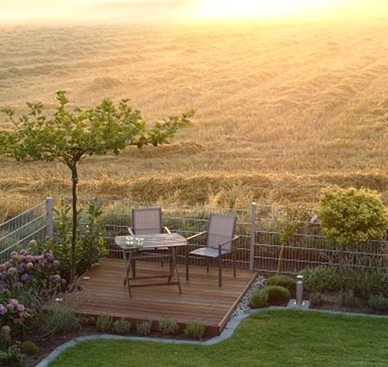 Gepflegter Garten mit Holzterrasse im Abendlicht